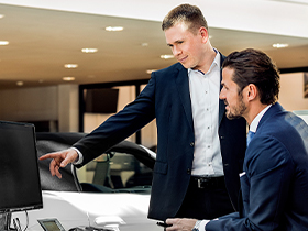Ein Mitarbeiter des Porsche Zentrum arbeitet am Schreibtisch einen neuen Mitarbeiter ein.